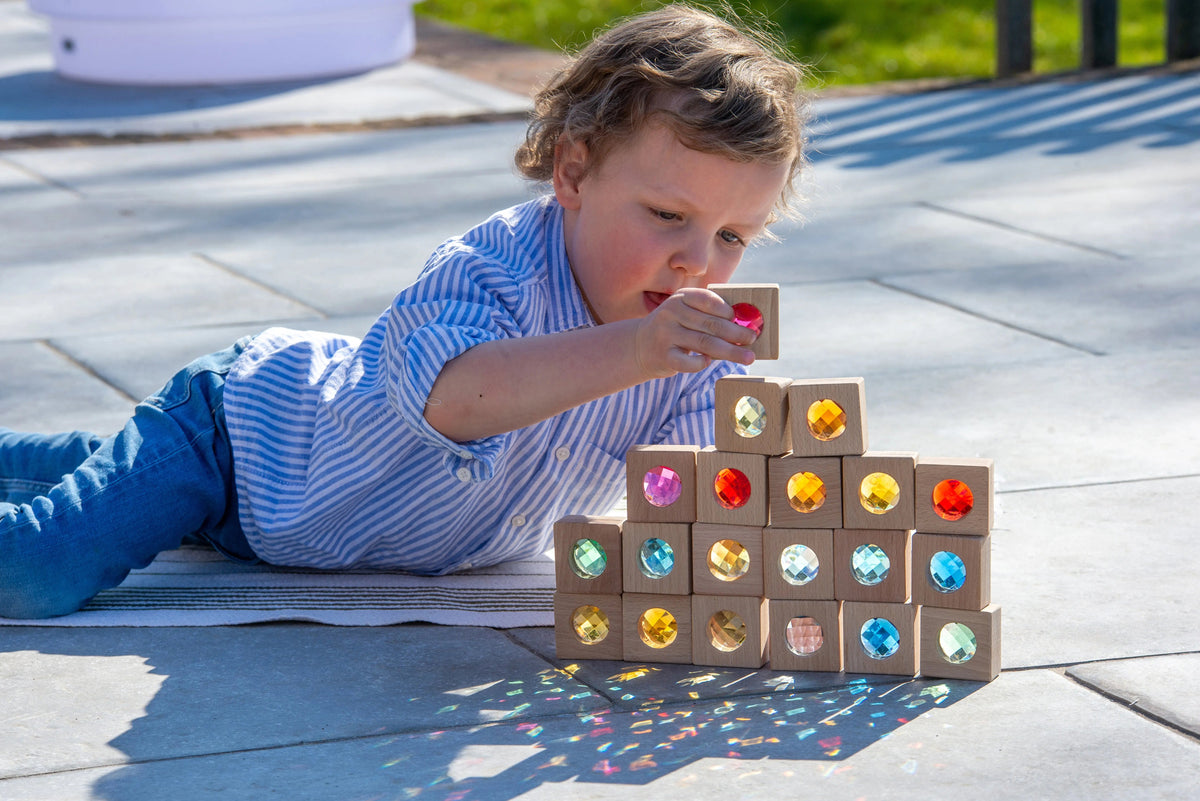 Dítě staví věž z kaleidoskopických dřevěných kostek TickiT