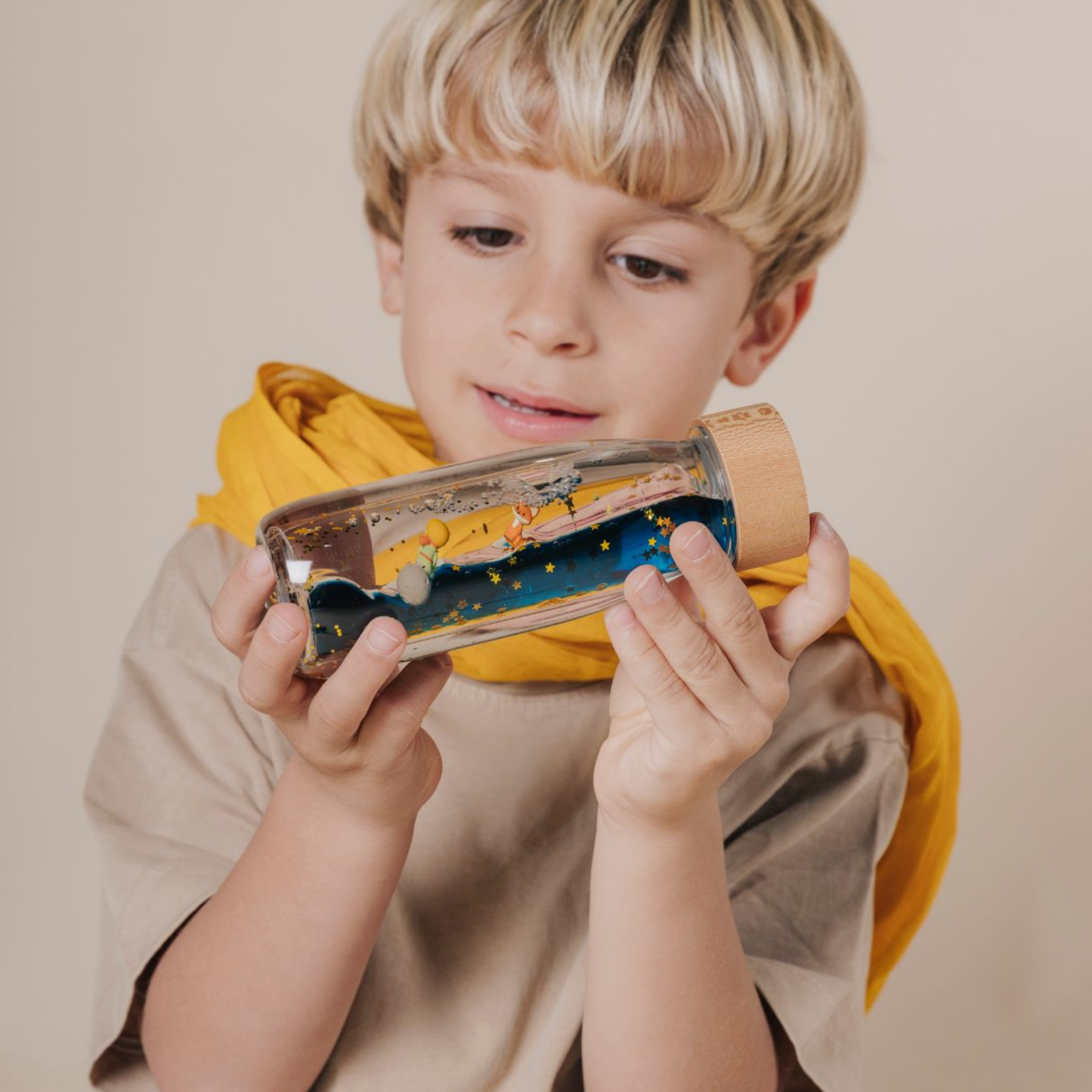 Dítě pozoruje senzorickou lahvičku Petit Boum Le Petit Prince s Malým princem a liškou